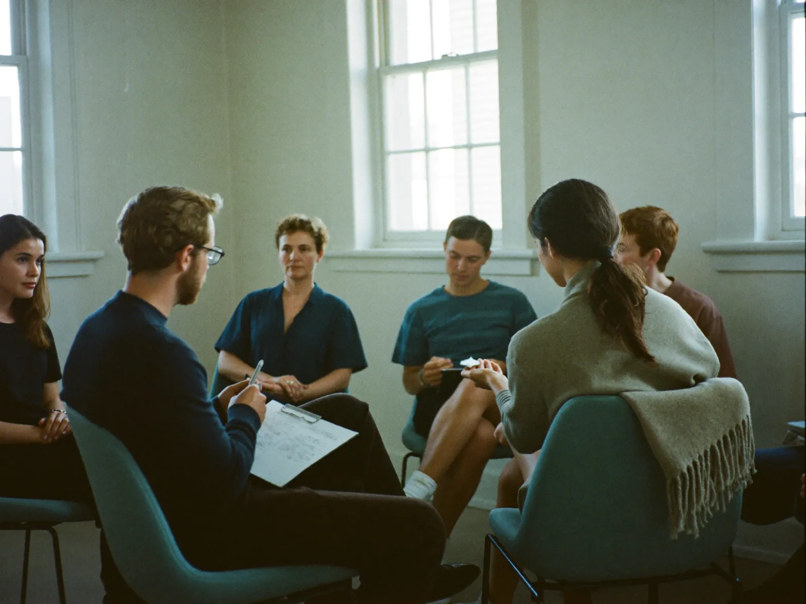 A moderator running a focus group with five seated participants